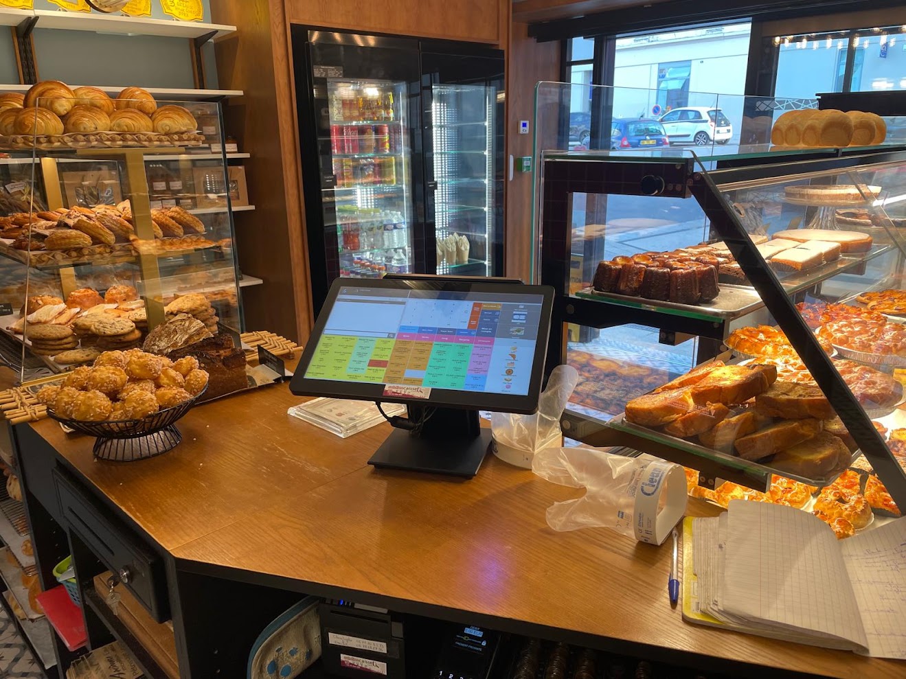 Caisse Linéo en service en boulangerie, derrière la vitrine des pains et viennoiseries